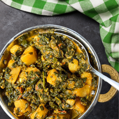 A vibrant Indian Spinach and Potato Curry dish, showcasing sautéed spinach and golden potatoes flavored with turmeric, cumin, and garlic. The colorful spices and herbs surrounding the dish highlight the benefits of plant-based diets for children.